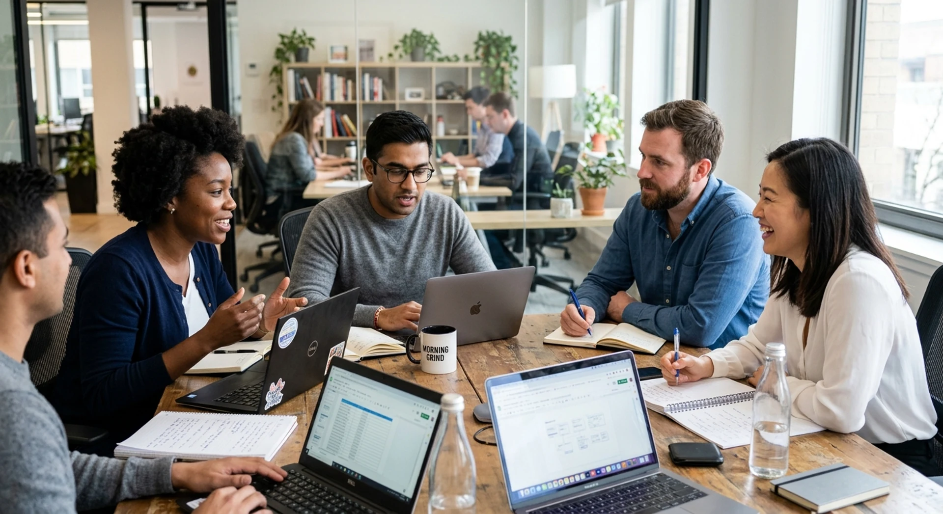 Fotografia editorial ultra-realista de equipe diversa em reunião matinal colaborativa ao redor de mesa com laptops e notebooks, luz natural de janela, foco nítido e detalhes precisos capturados em Canon EOS R5.
